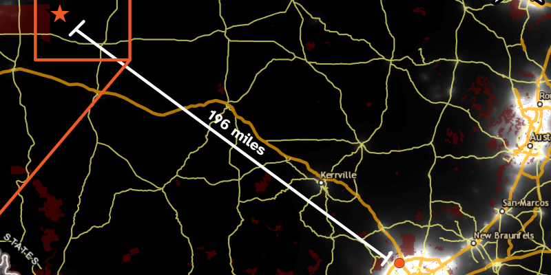 A screenshot of a map of central Texas, with a background of light pollution levels overlayed by a road network and a line showing the distance from San Antonio to a rural point